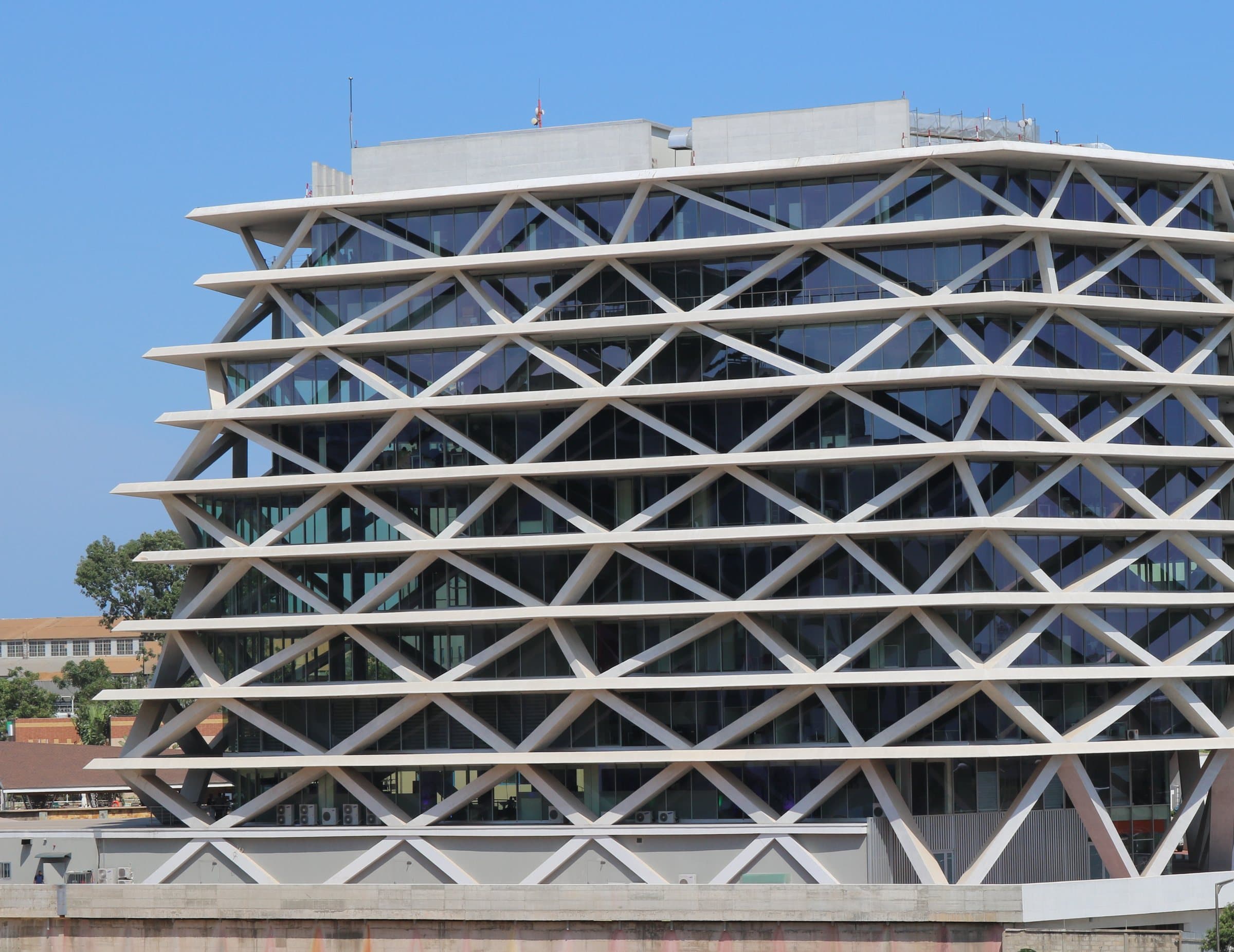 White diagrid facade of a glass office block against a clear blue sky in Airport Residential Area, Accra